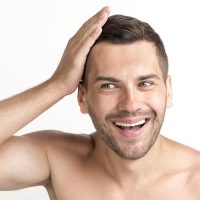 smiling-young-shirtless-man-touching-his-hair-white-backdrop-min